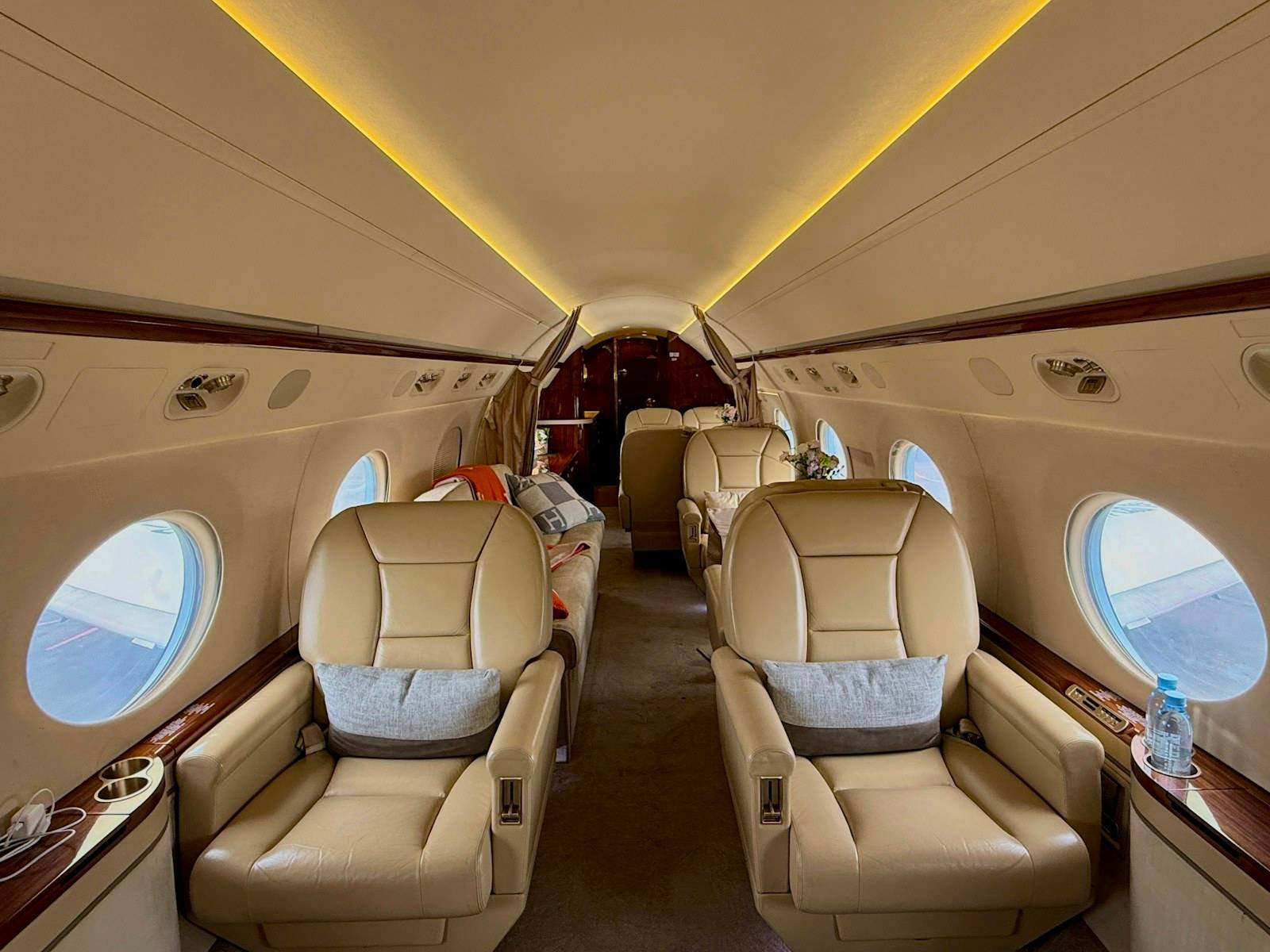 Cream leather seats along the aisle of a private jet cabin with warm overhead lighting