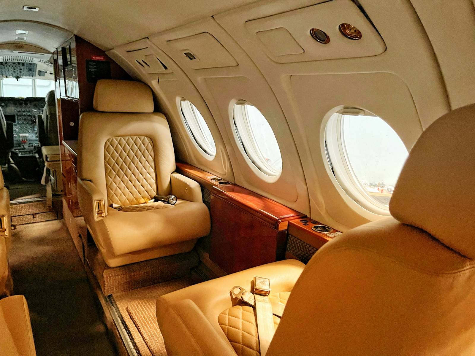 Cream leather club seats and wood veneer inside a midsize private jet cabin