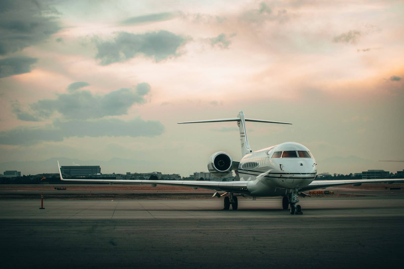 A super-midsize business jet parked on the ramp beneath a soft dusk sky