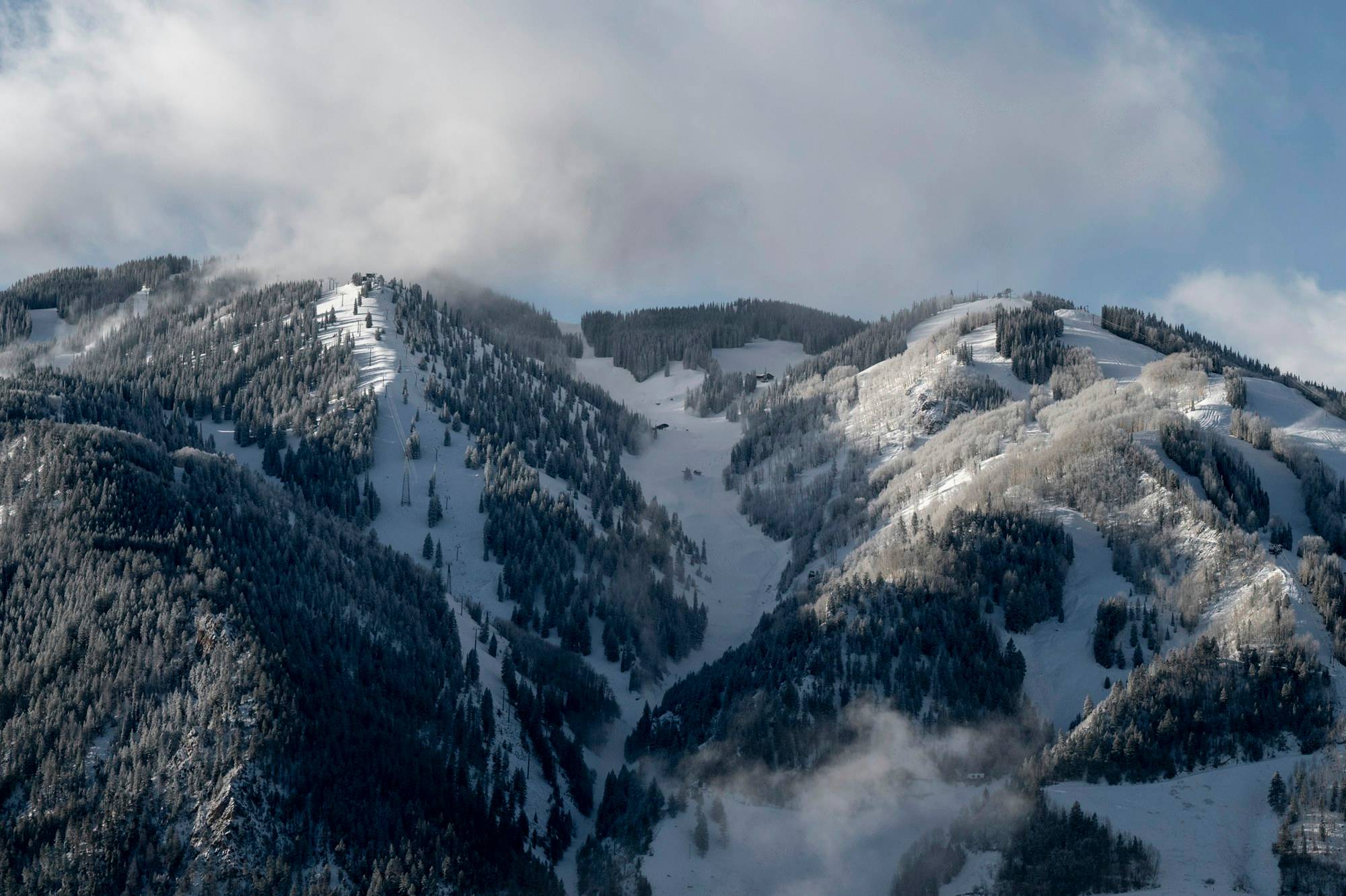 Snow-covered ski runs on Aspen Mountain under low winter cloud